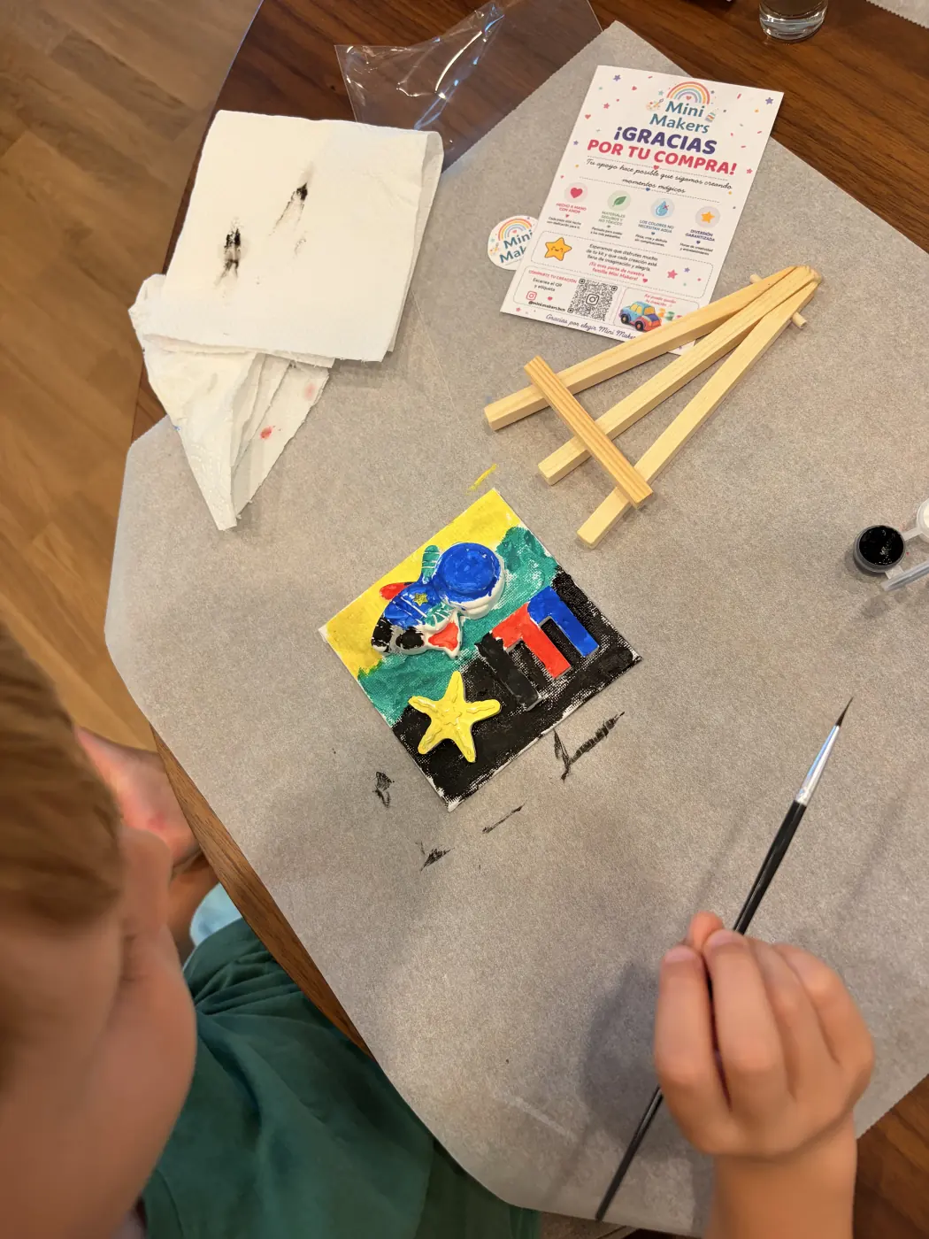 Colourful blue astronaut and letter E artwork in progress beside a mini easel and Mini Makers card.