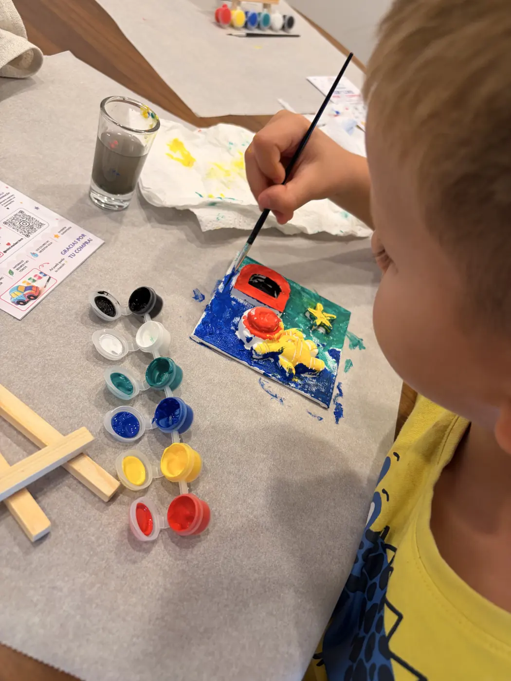 A child adds finishing touches to a yellow astronaut artwork with a red letter D and star.